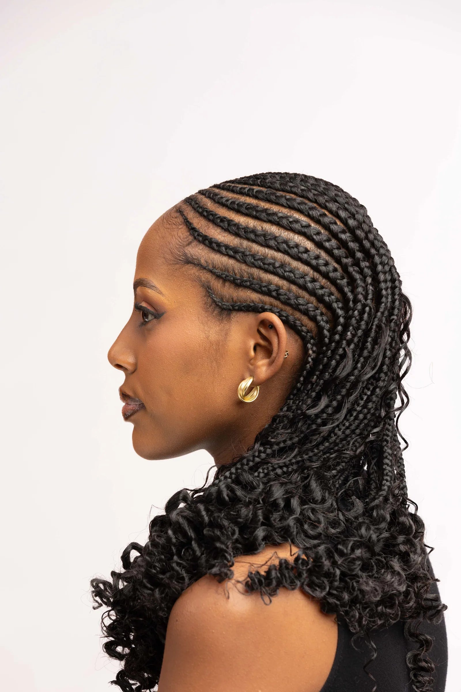 Profile showing neat cornrow parting and a curled braid finish